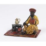 Bergman style cold painted bronze, depicting a gentleman seated on a rug smoking a pipe and