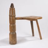 Wooden coconut husking stool, with metal capped point to the raised turned front leg, shaped seat,