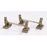 Pair of novelty knife rests, each with cast depcition of two seated dogs connected by a central bar,