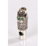Silver whistle in the form of a cats head with green eyes