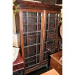 Edwardian mahogany bookcase, the down-swept pediment above two astragal glazed doors opening to