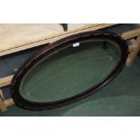 Simulated rosewood mirror, the oval beaded frame housing the bevelled mirror plate, 82cm x 57cm