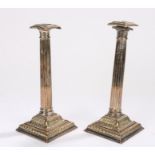 Pair of plate on brass candlesticks, the square gadrooned sconces above reeded stems and reeded