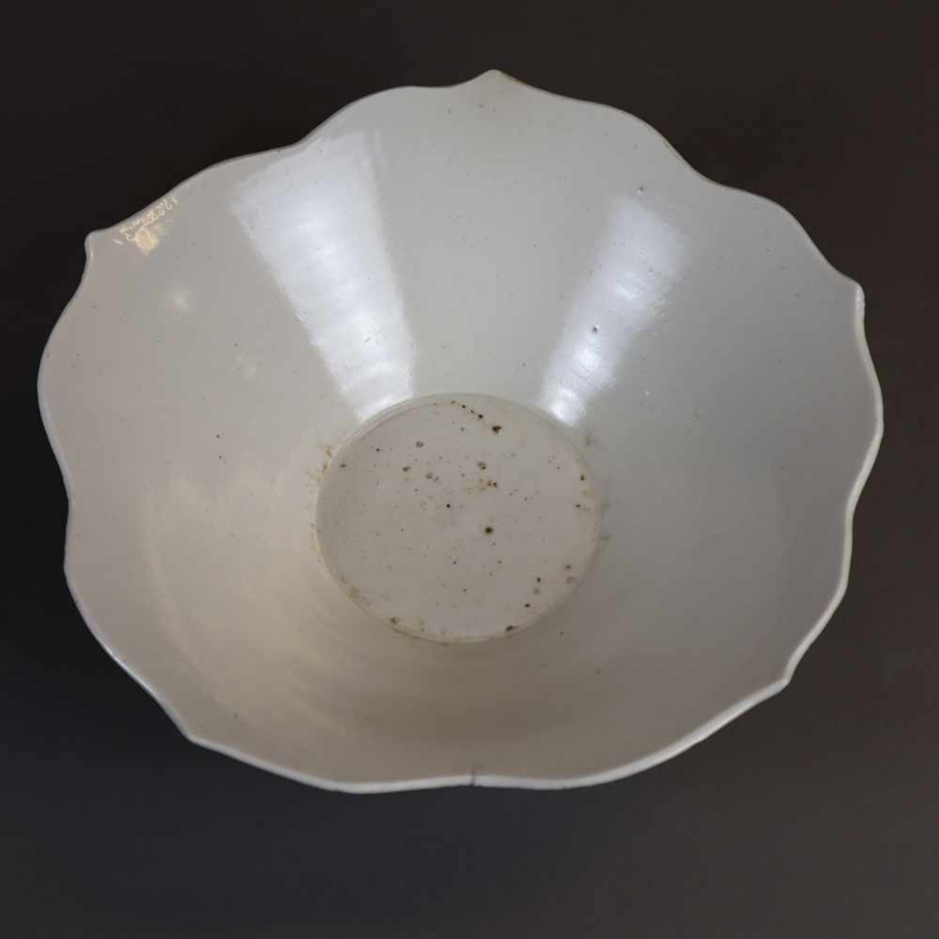A Dingyao Flower-Shaped Bowl - China, Liao-Dynastie, off white glaze, appr.25 cm diam., age and use遼