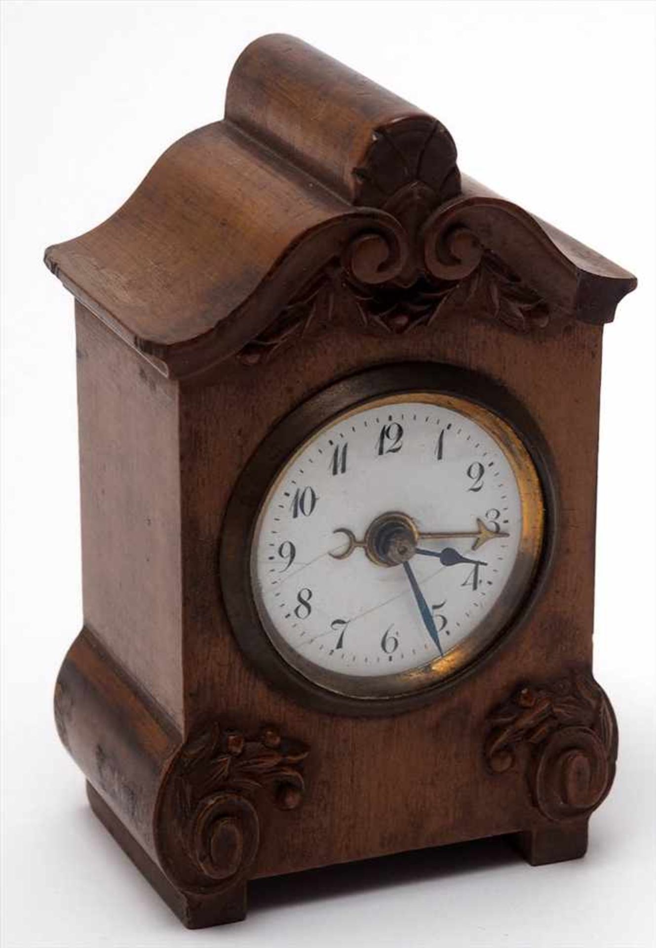 Wecker, um 1900Fein geschnitztes Nussbaumgehäuse mit eingelassener Uhrtrommel. Weißes