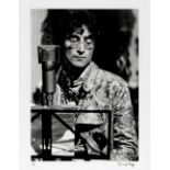 David Magnus (British, B.1944): A black and white silver gelatin print of John Lennon at a microp...