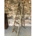 A Pair of antique adjustable wooden ladders. Writing to the side. A FRAME HEIGHT APPROX 175CM,