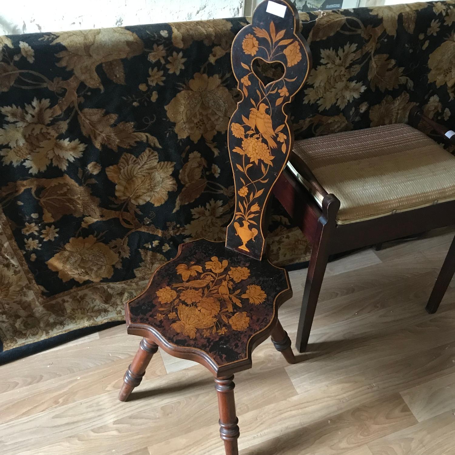 An antique arts and crafts spinning wheel chair. Ornately designed with a flowers and birds.