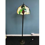 A Tiffany style standard lamp. Ornately designed with grapes and vines. Working. Measures 162cm in