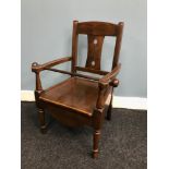 A child’s antique arts and crafts chair with safety bar.