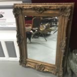 A Large ornate gilt framed bevel edge mirror. Measures 128x98cm