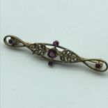 A 9ct gold ladies ornate brooch set with ruby gems and seed pearls