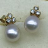 A pair of 18ct gold earrings set with one large pearl and 3 diamonds to each.