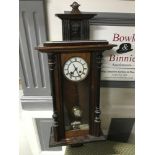 A Victorian wall clock within a mahogany casing, Enamel face, key and pendulum.