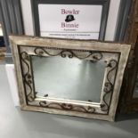 A Solid wood, drift wood effect and wrought iron scroll framed mirror. Measures 92x112cm