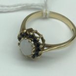 A Beautiful 9ct gold ladies ring set with a single opal and surrounded by a Sapphire cluster. Size