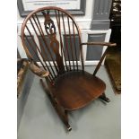 A Dark elm wood Ercol rocking chair with cushions