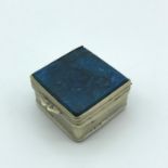 A white metal pill box designed with two square blue Lapis Lazuli stones. 1.6x2.7x3cm