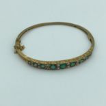 A Birmingham 9ct gold ladies bangle, Designed with 9 various sized emerald stones and seed pearls.