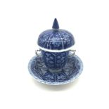 A Chinese porcelain blue and white covered tea cup with matching saucer. Cup has Two handles. Marked