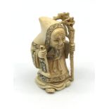 A 19th century Japanese hand carved netsuke figure, Old man holding a scroll and walking stick,