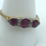 An 18ct gold ladies ring set with 3 Ruby stones and four diamonds. Ring size T.