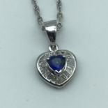 An 18ct white gold necklace with a 18ct white gold diamond and sapphire heart shaped pendant, Weighs