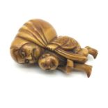 A 19th century hand carved Japanese netsuke, Man carrying a large faced figure, Signed to the base