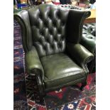 A Green leather Chesterfield wing back arm chair.