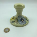 A William Moorcroft floral design candle stick. Impressed marking and sticker to the base.