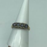 A Ladies 9ct gold ring set with 4 pale purple stones surrounded by diamond cluster. Ring size P.