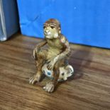 An antique Cold painted bronze monkey sitting on a chanty. Stamped to the base. Measures 3.5cm in