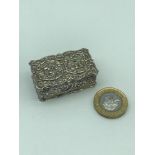 A London silver ornate pill box depicting cherubs to the top of the lid. Produced by A Chick &