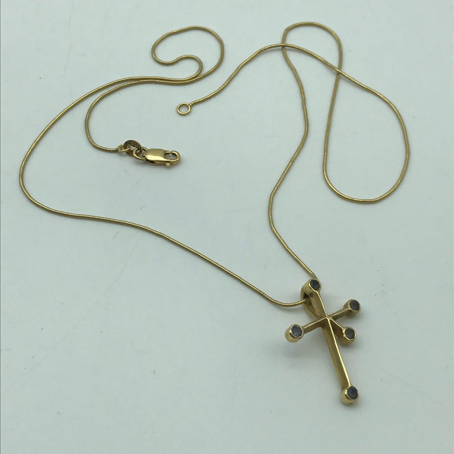 An 18ct gold necklace with an 18ct gold cross like pendant with clear stones. Weighs 5.45grams