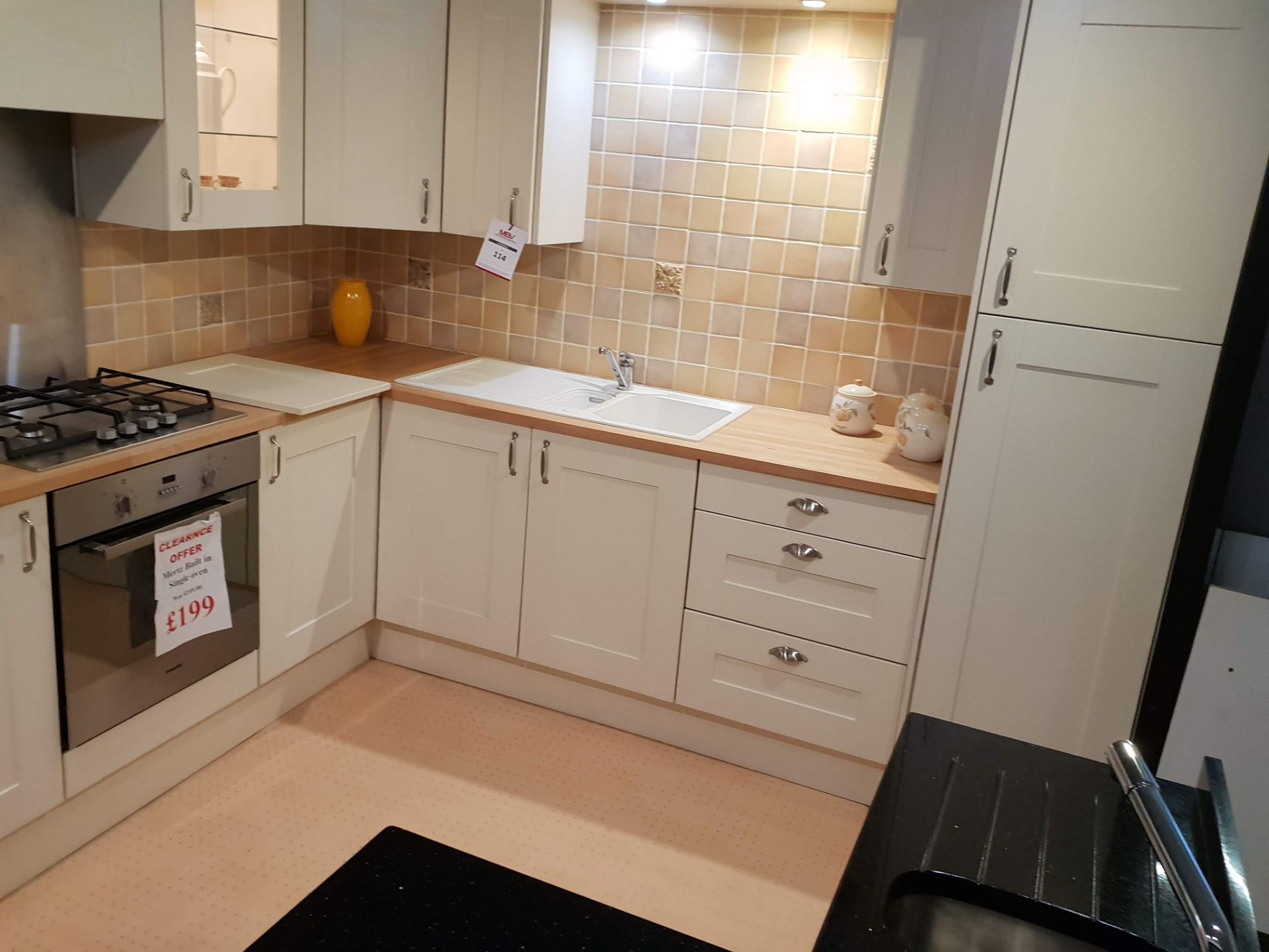 White kitchen display with beech effect and black work surfaces.