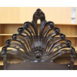 A Rococo style ebonised bed with carved shell headboard on cabriole legs and ball and claw feet