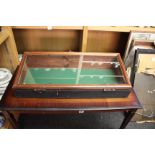 A stained pine counter top display cabinet (78cm x 35cm), with glazed top and brass handles