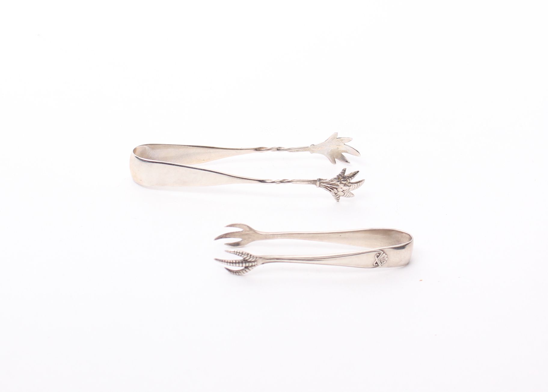 Two pairs of sterling silver sugar tongs, Birmingham 1927 and Sheffield 1935.