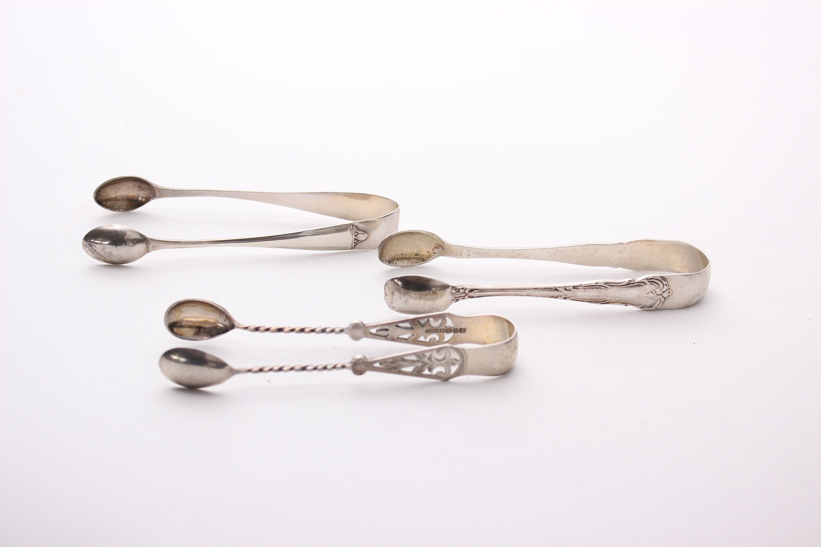 Three pairs of sterling silver sugar tongs; together with a pierced and footed silver salt (vacant