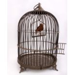 A late 19th early 20th century ornate brass dome shaped bird cage containing a taxidermy songbird on