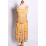 A 1920s sleeveless yellow silk cocktail dress, with beaded swags of flowers, a lattice pattern