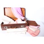 A collection of early 20th Century dressmaking fabric within a leather suitcase, comprising pale