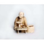 A Japanese carved ivory Okimono of a seated man, Meiji period, the figure seated before a low