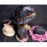 An early 20th Century straw hat decorated with feathers and faux fruit; an early 1920s black straw