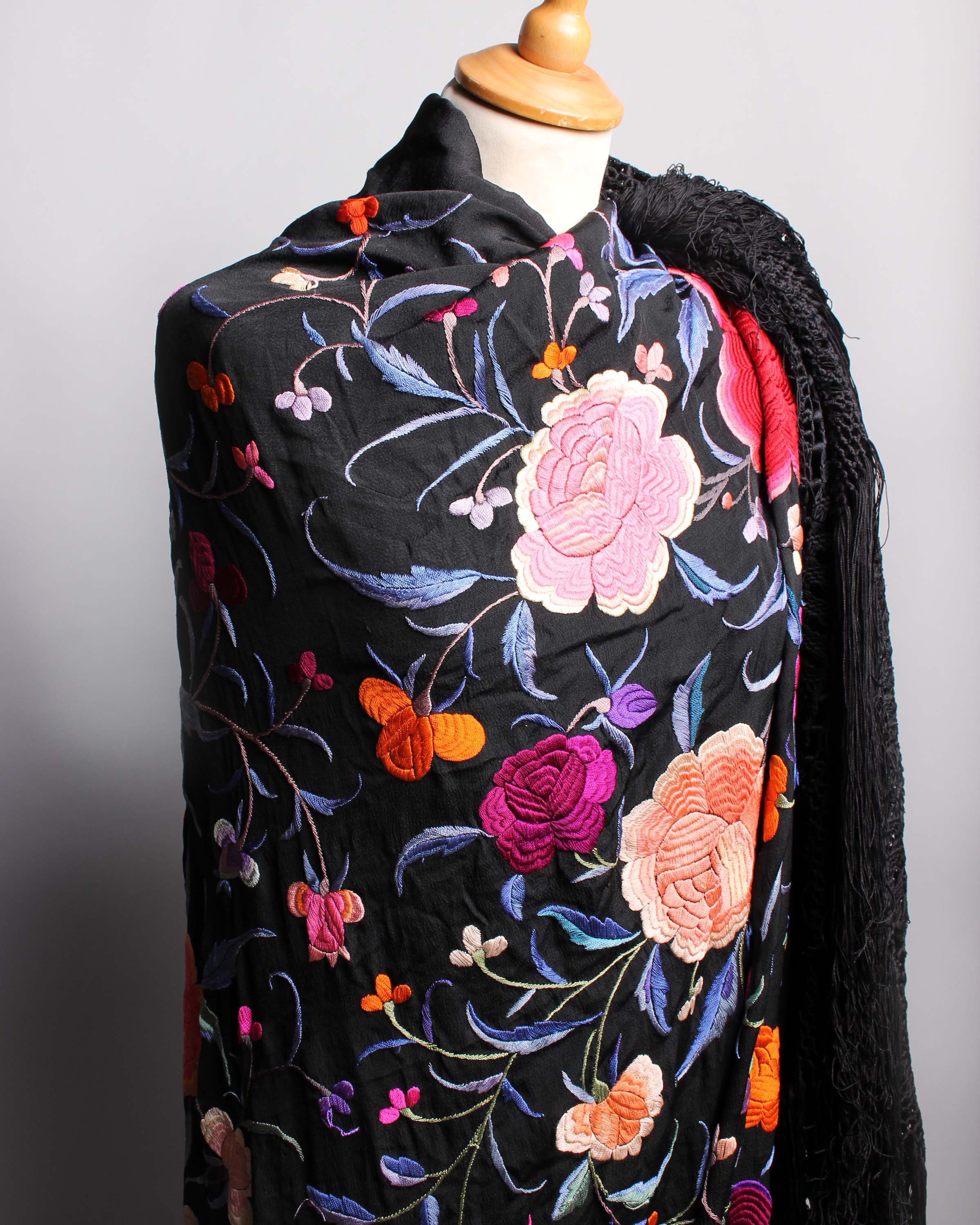 A late 19th Century black silk fringed Chinese shawl, embroidered with large pink and red flowers