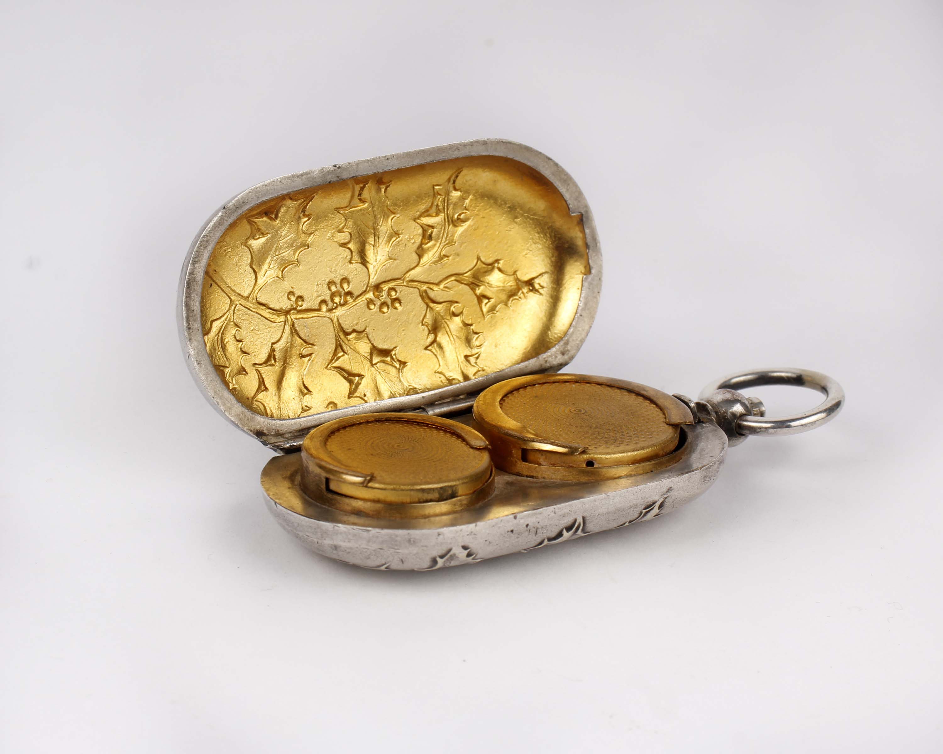 A silver plated double sovereign case with gilt interior and raised floral decoration.