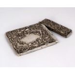An Edwardian sterling silver card case with raised and engraved floral decoration and vacant central
