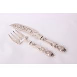 A pair of Victorian silver fish servers with pierced blade and tines to a C scrolling handle, by