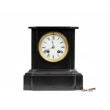 A black slate mantle clock by T. Hutchings. White enamel face with roman numeral markers and 8 day