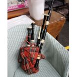 A set of modern bagpipes with red tartan cover.